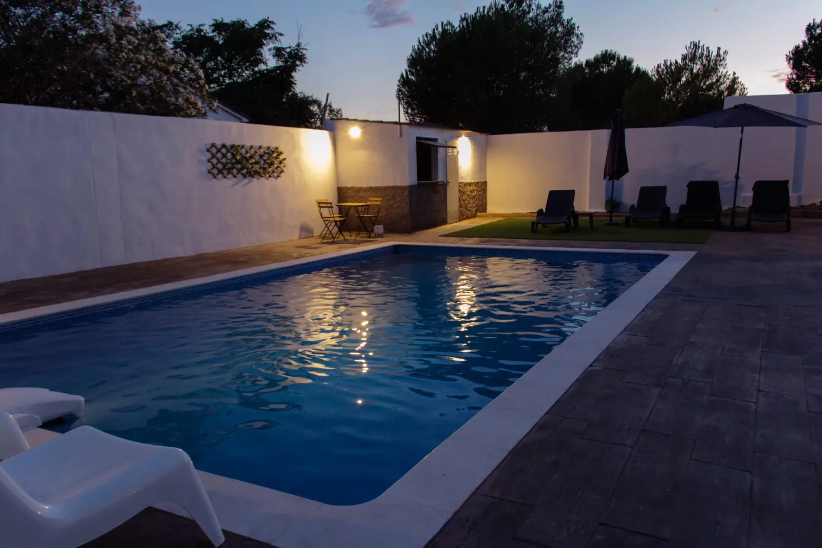 Piscina al atardecer con el banco de obra junto al jardín