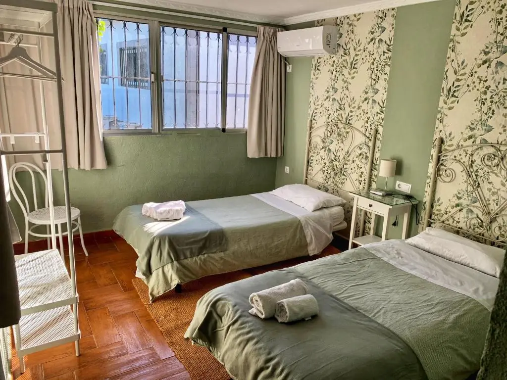El dormitorio de las flores a plena luz de día, con las dos camas y la ventana al patio